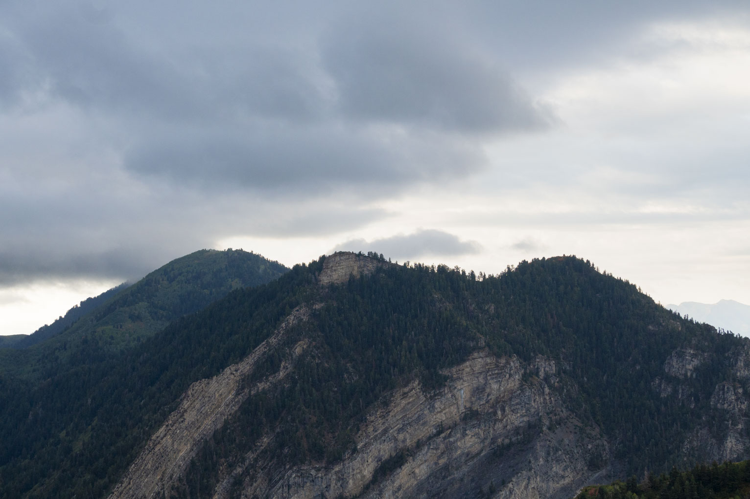 The piney rocky heights of three mountain peaks in the cloudy morning light